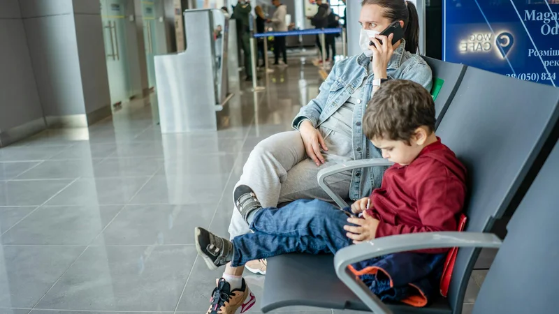 Mutter mit Kind am Flughafen-Terminal, Telefon in der Hand